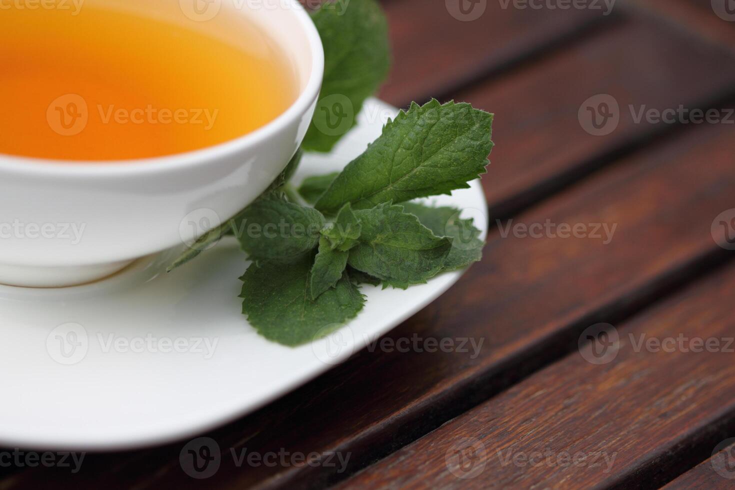 a cup of tea on a saucer with a leaf on it photo