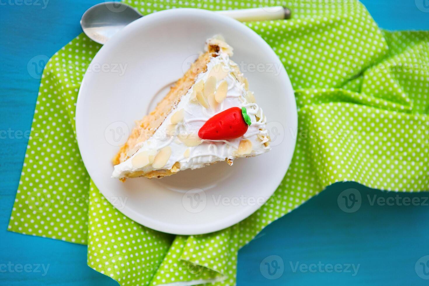 Piece of carrot cake with icing and little carrot photo