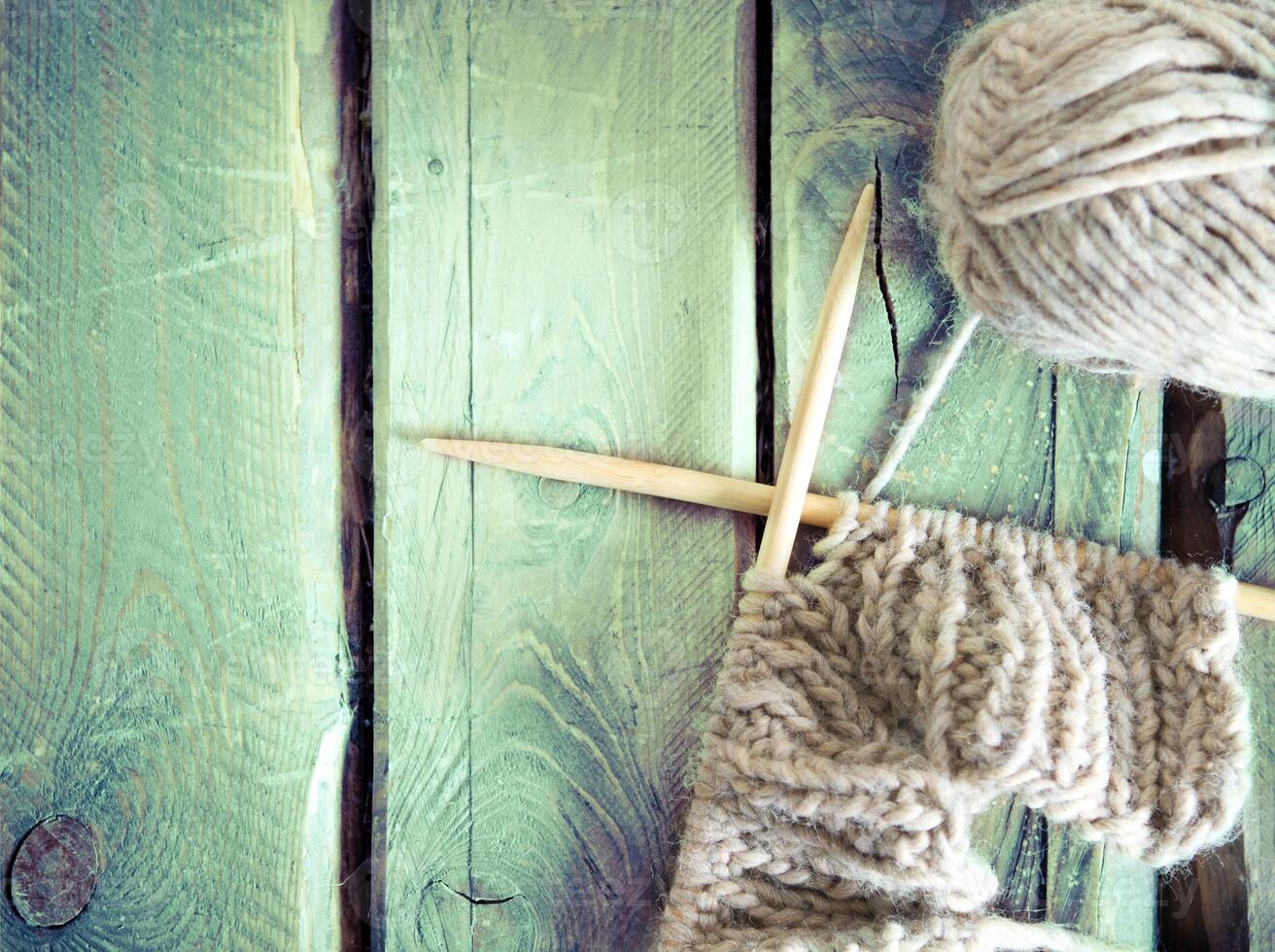 Colorful ball of yarn and knitting on a wooden table photo
