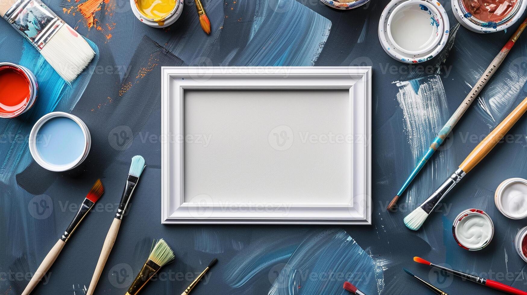 Art supplies on blue-painted canvas with white frame mockup. Artist workspace photoframe template advertising image. Painter tools pictureframe border mock up product photorealistic photo
