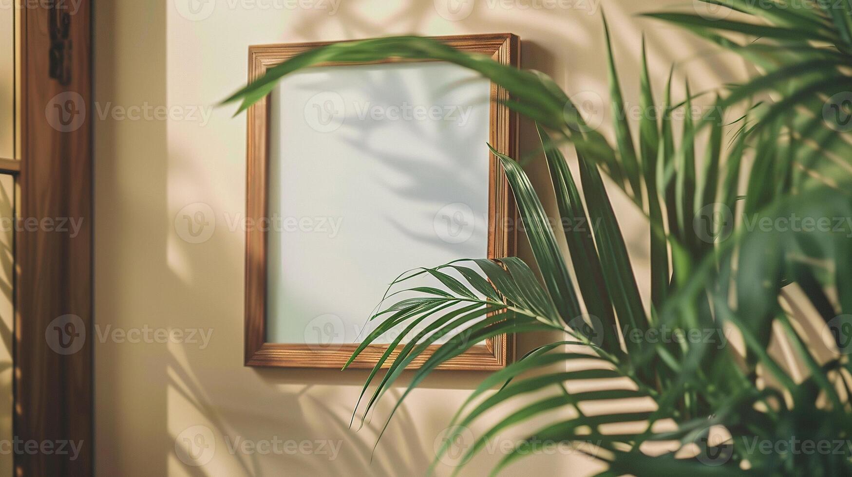 Wooden picture frame mockup on beige wall surrounded by lush green leaves. Sunlight leaf shadows pictureframe template advertising image. Tropical border mock up product photorealistic photo
