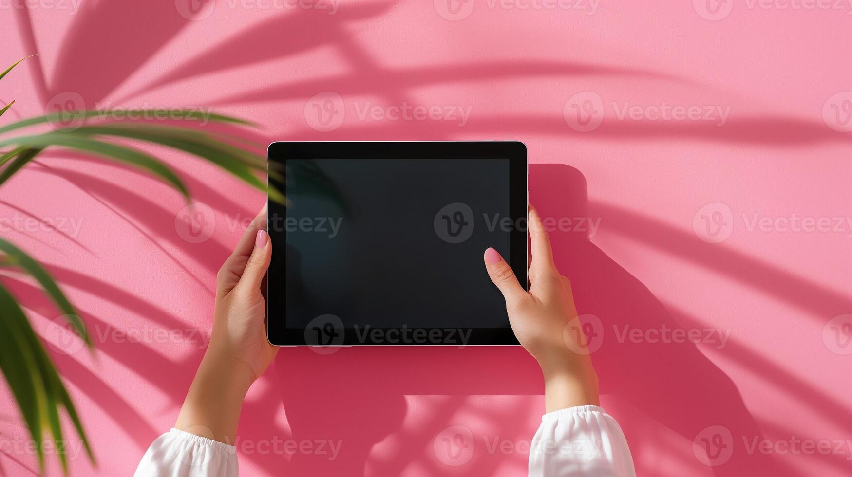 Female hands holding tablet device mockup against pink wall leaves shadows. Digital content. Tech, creative and lifestyle theme template advertising image. Mock up product photorealistic photo