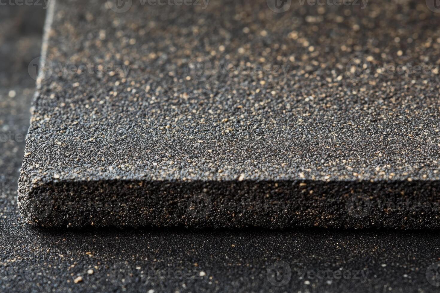 Close-up of textured black sandpaper on a work surface highlighting fine grit and surface detail photo