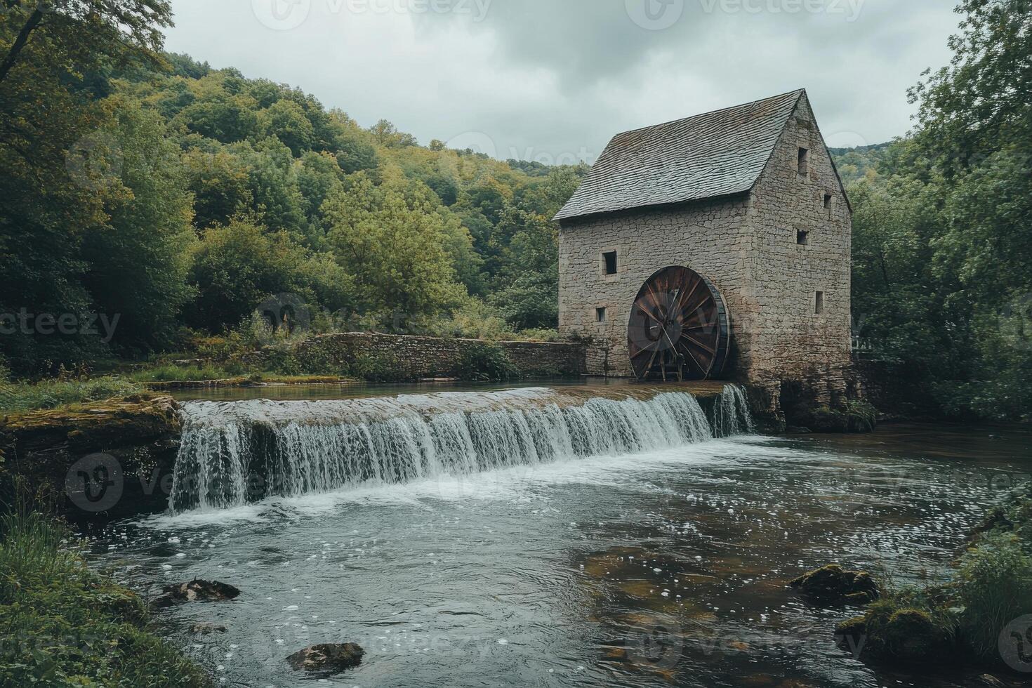 Historic watermill beside a tranquil stream with cascading waterfall surrounded by lush greenery photo