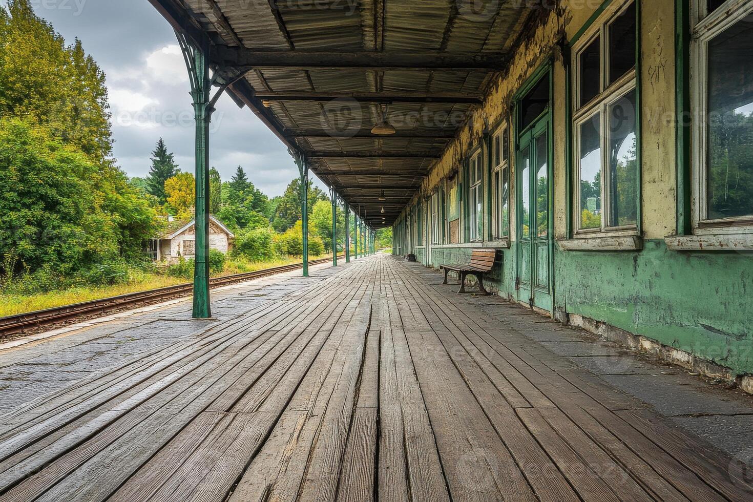Deserted train station platform with wooden benches and overgrown backdrop on a cloudy day photo