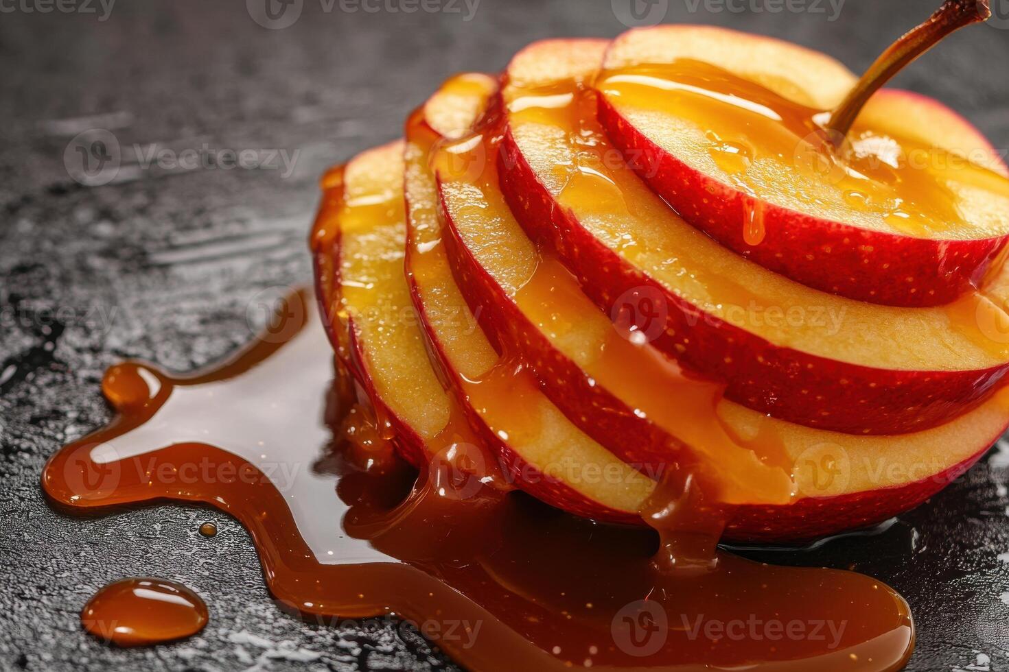 Sliced red apple drizzled with caramel on a dark surface during a culinary presentation photo