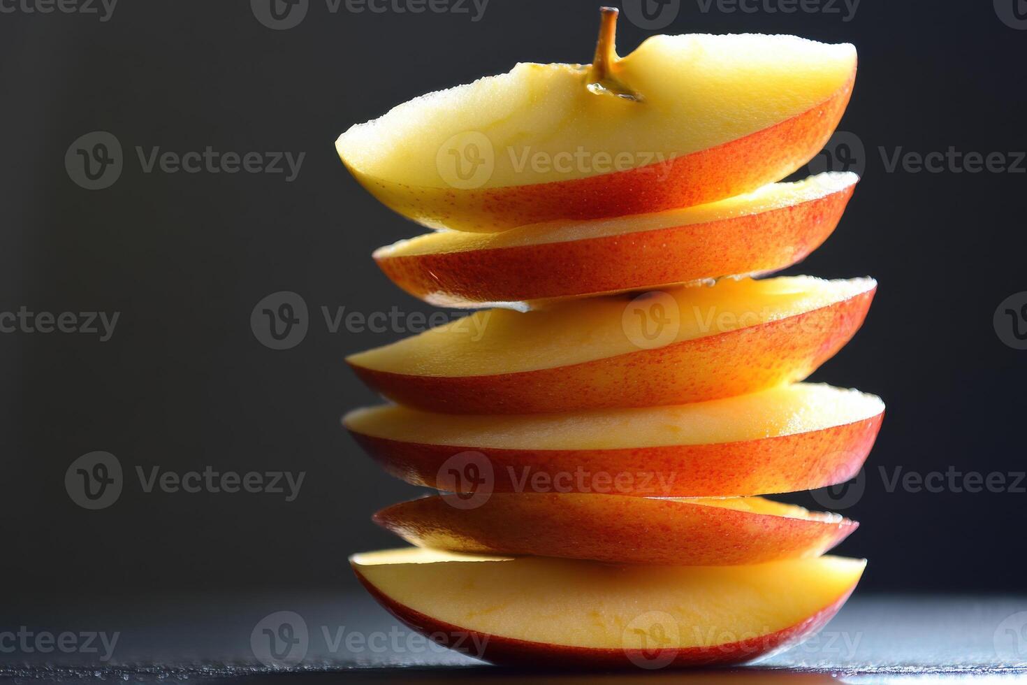 Sliced red apple stacked on a dark surface with dramatic lighting showcasing its texture photo