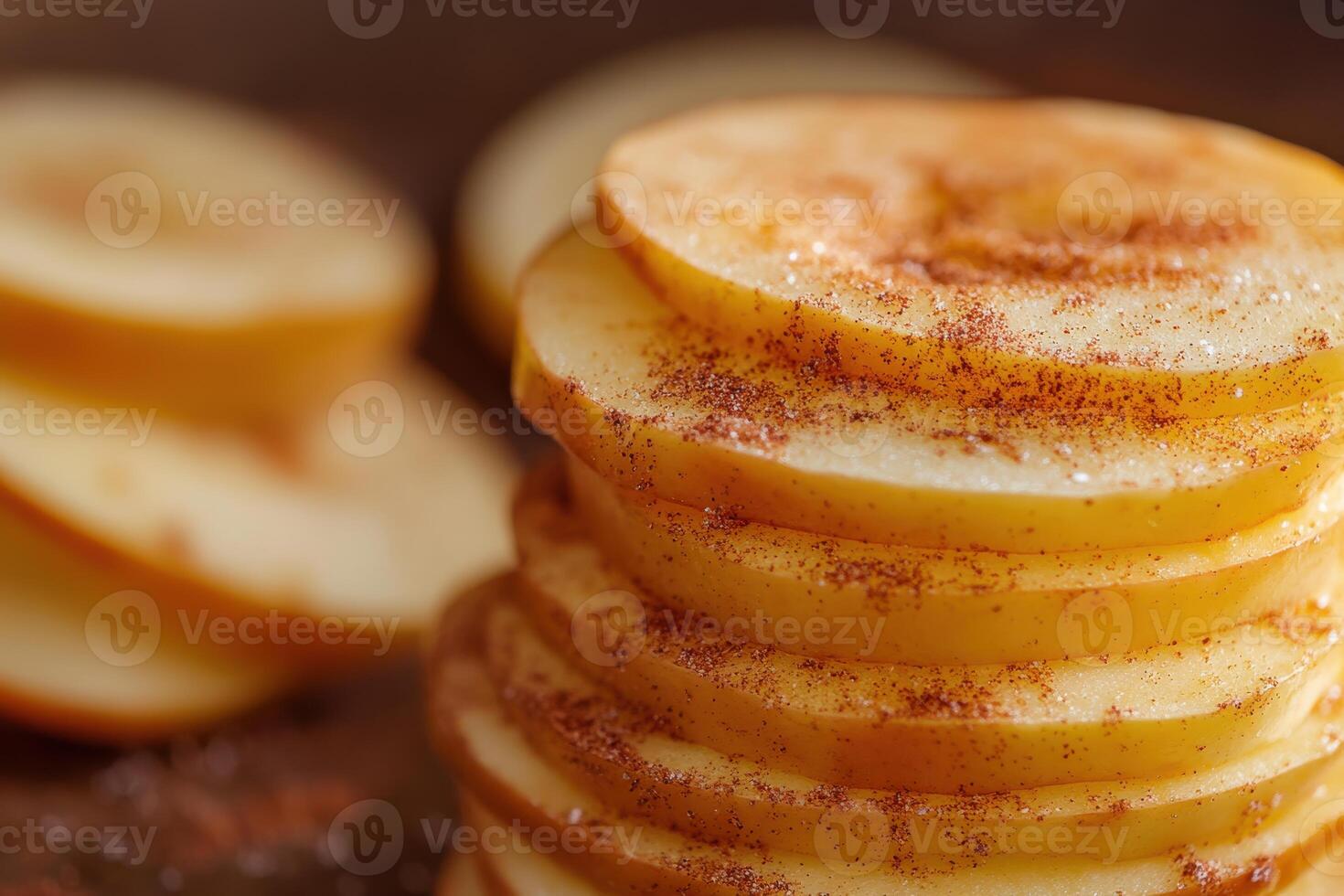 Stacked slices of apples coated with cinnamon arranged on a wooden surface in natural light photo