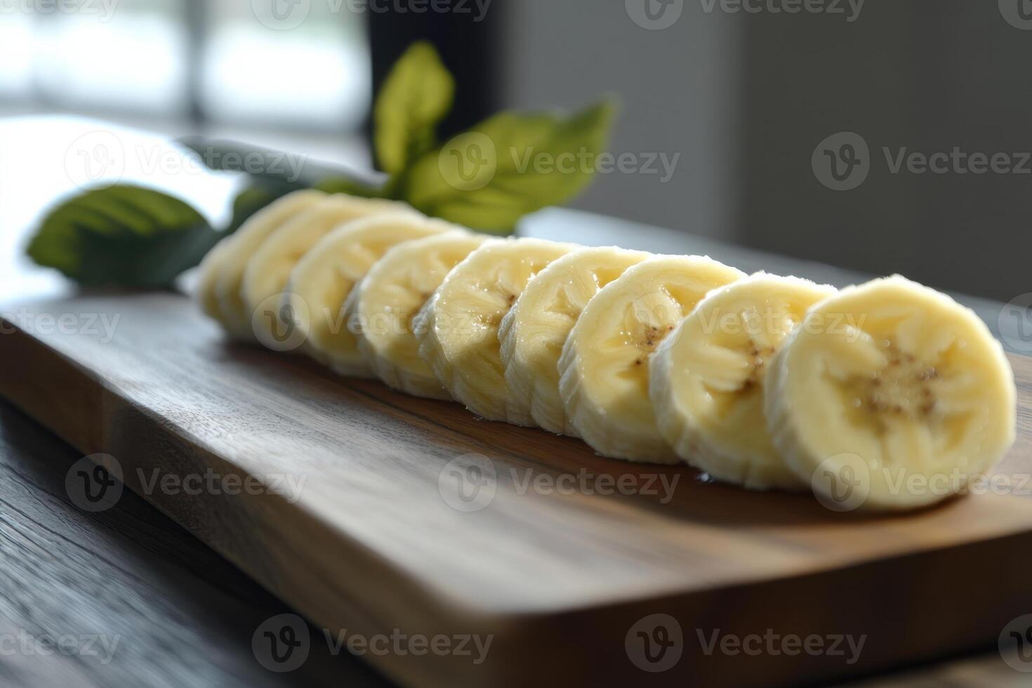 Sliced bananas arranged neatly on a wooden cutting board with natural lighting in a kitchen photo