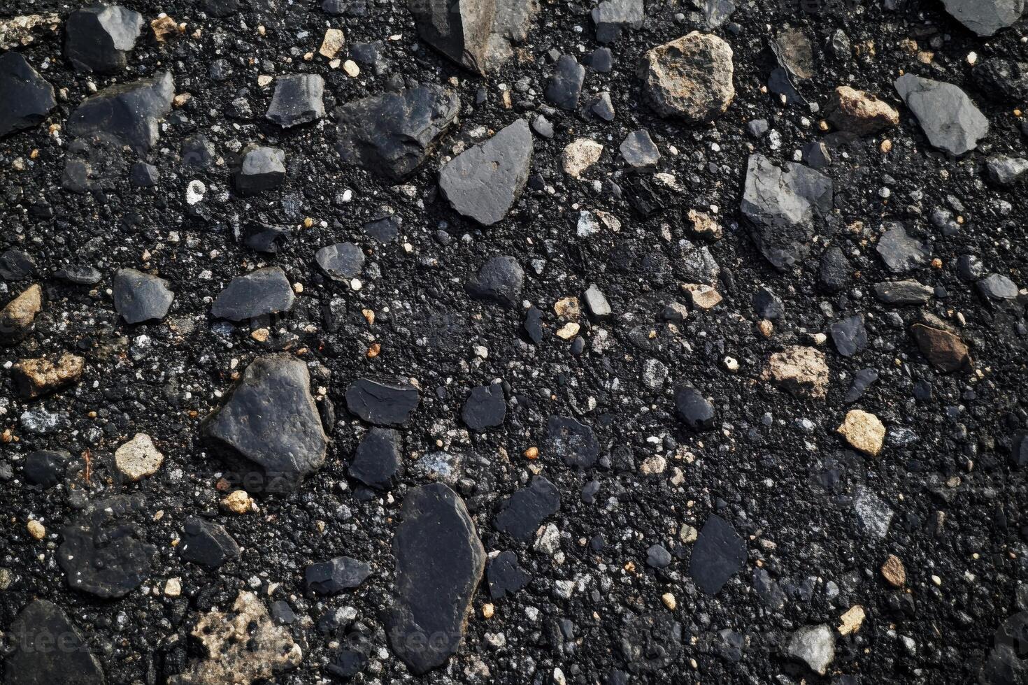 Close-up of a textured asphalt surface with various stones and gravel during daylight hours photo