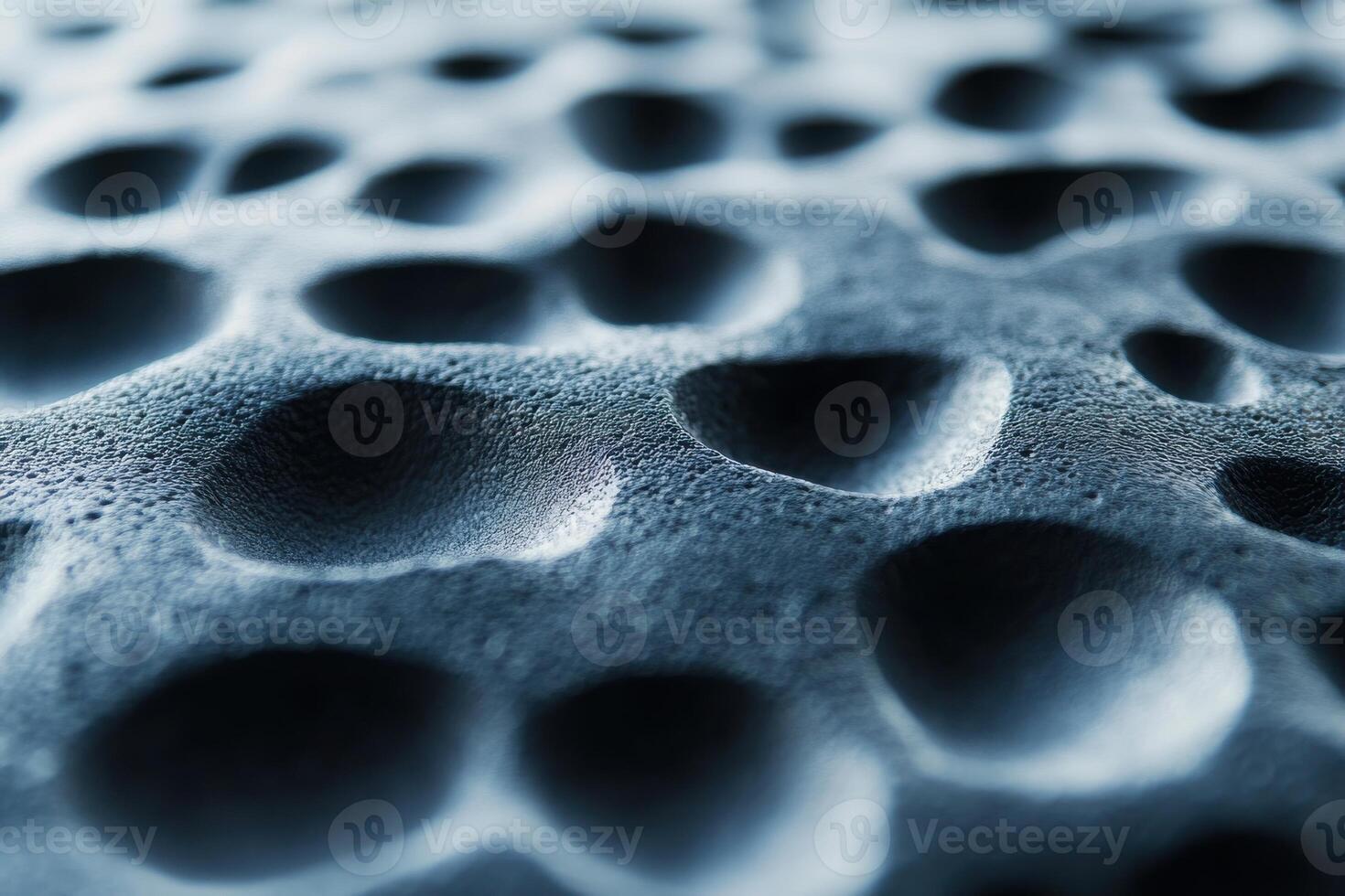 Close-up of textured surface with numerous shallow indentations and shadows under soft lighting photo