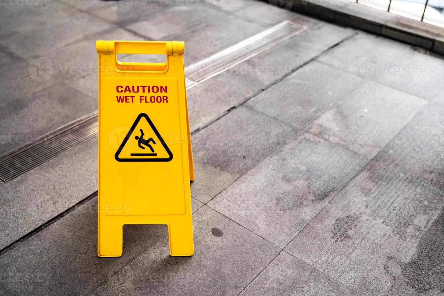 Yellow Caution slippery wet floor sign on the wet ground. Copy space. photo