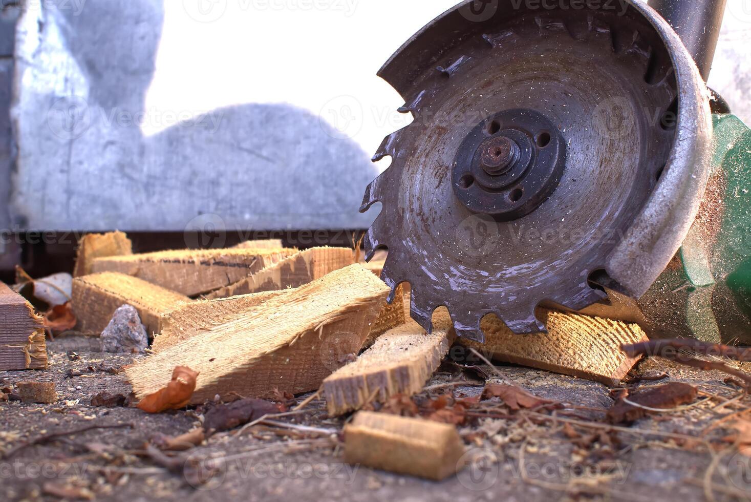 Circular saw blade slices through logs, scattering wood shavings and debris around a rustic workshop photo
