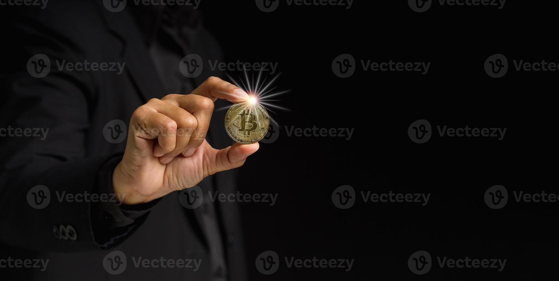 Businessman holding a bitcoin coin while standing over a black background photo