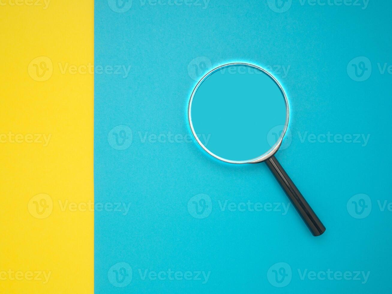 Top view of a magnifying glass on a yellow and blue background photo