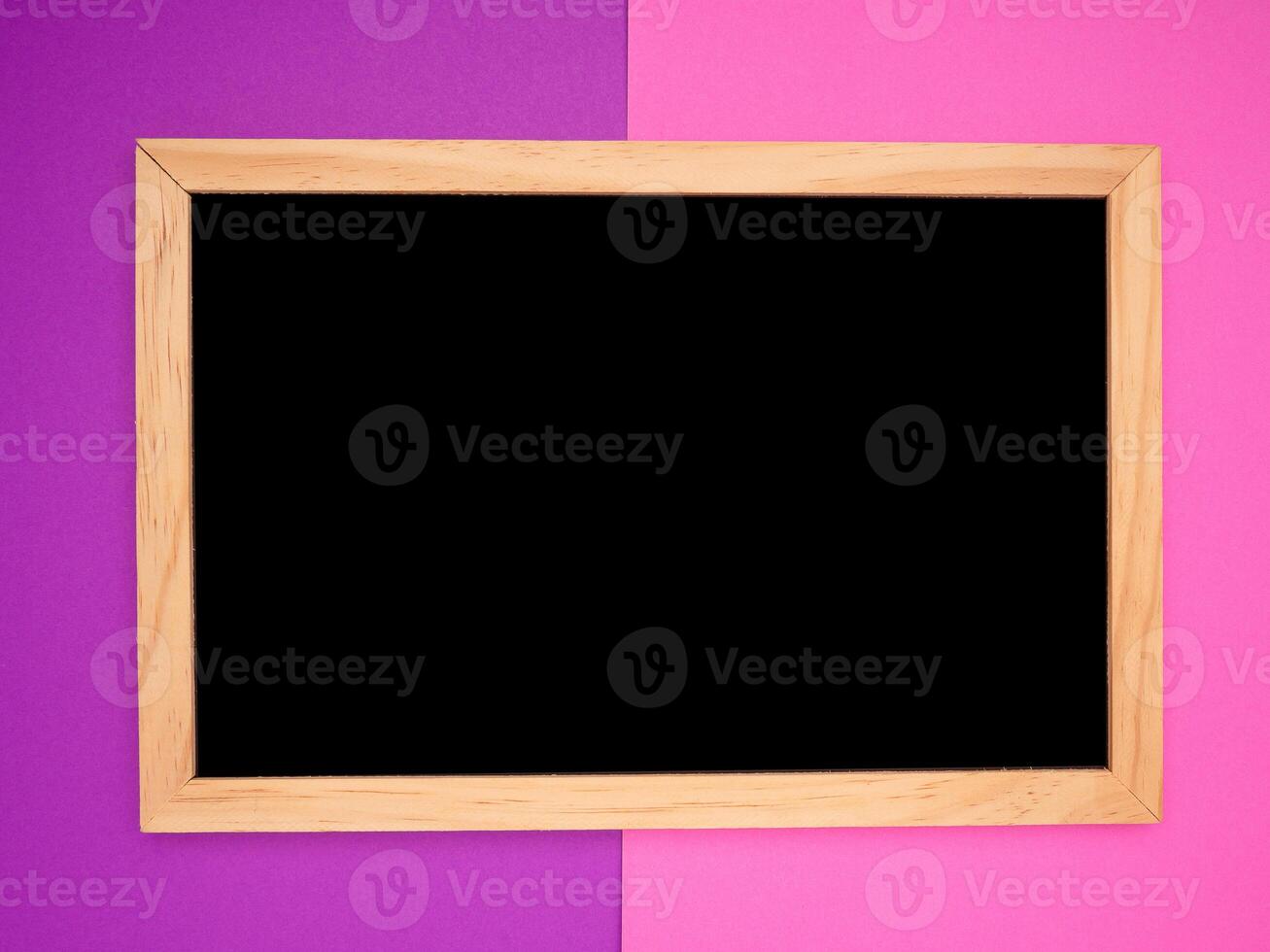 Top view of empty blackboard with a wooden frame over a purple and pink background photo