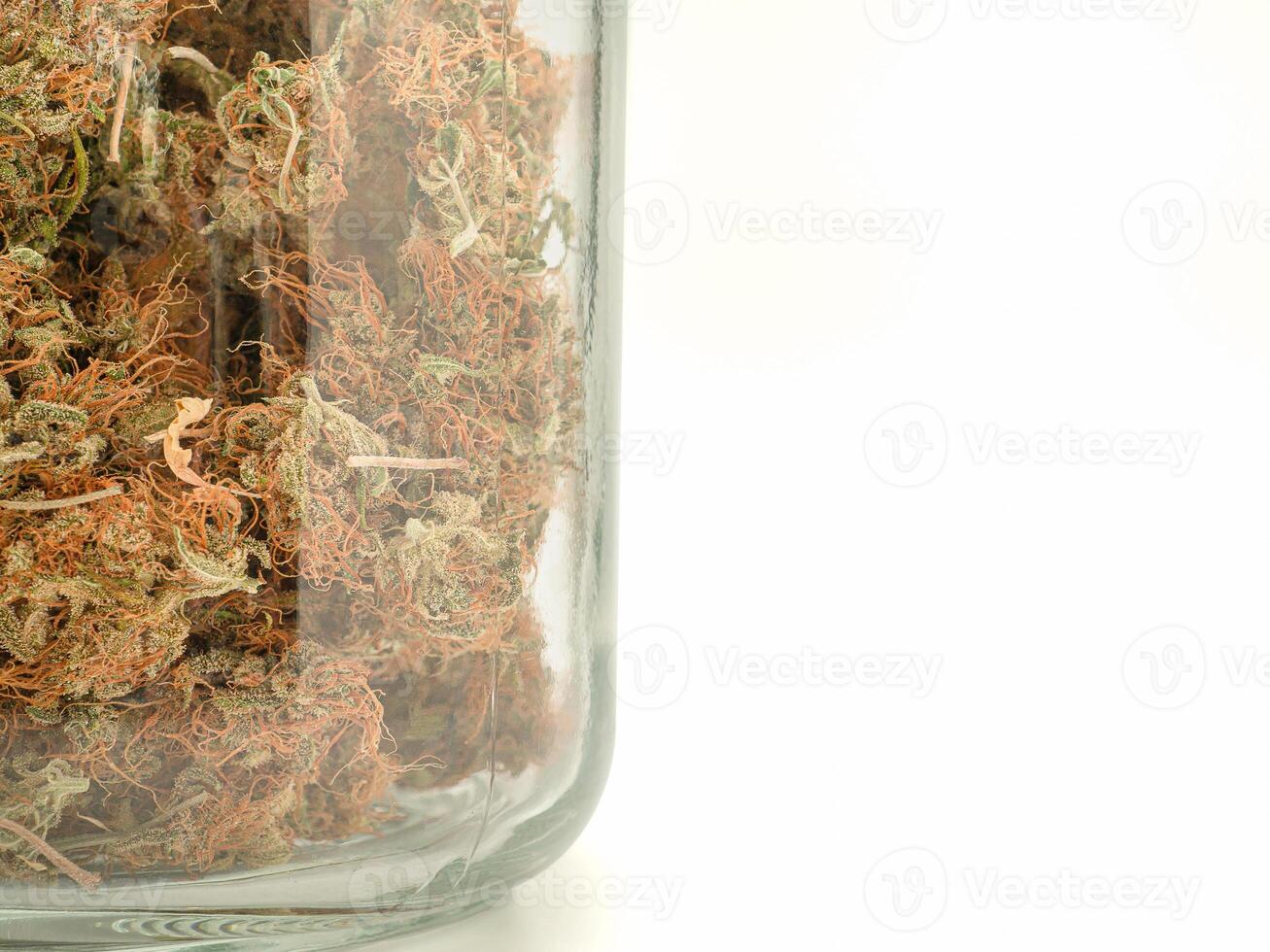 Dry cannabis buds flower in a jar glass over a white background photo