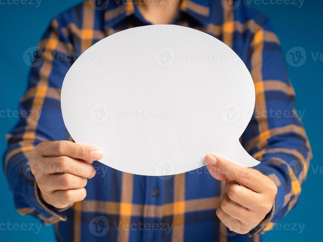 Hand holding of an empty white speech bubble against a blue background photo