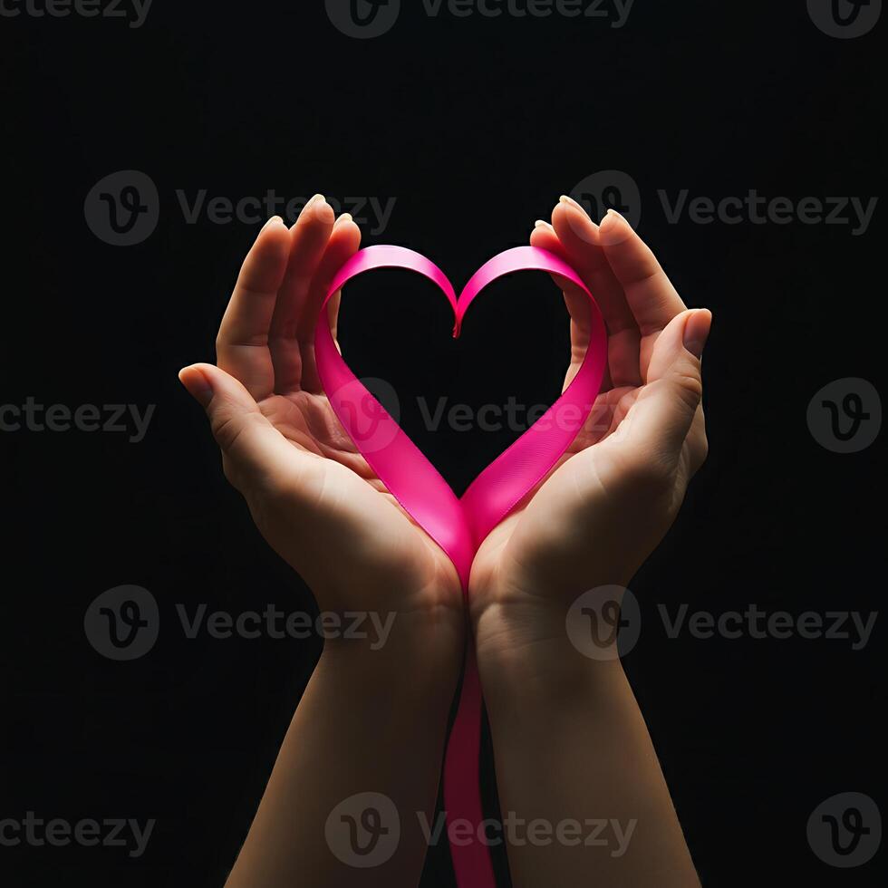 A pair of hands holding a pink ribbon in the shape of a heart photo