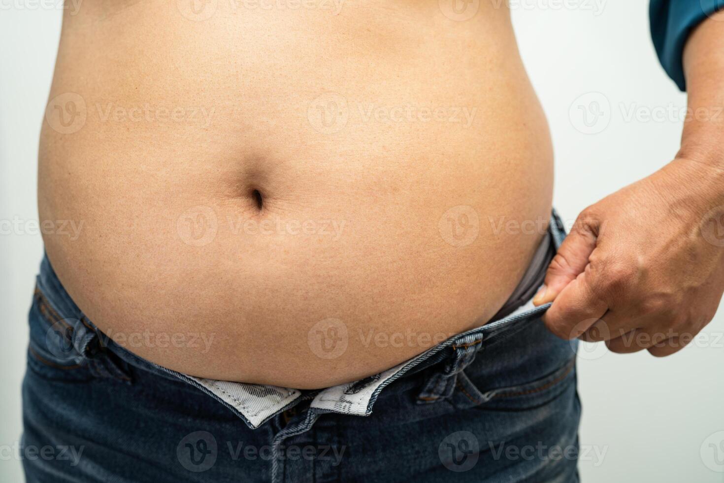 Overweight Asian woman show and use hand to squeeze fat belly. photo