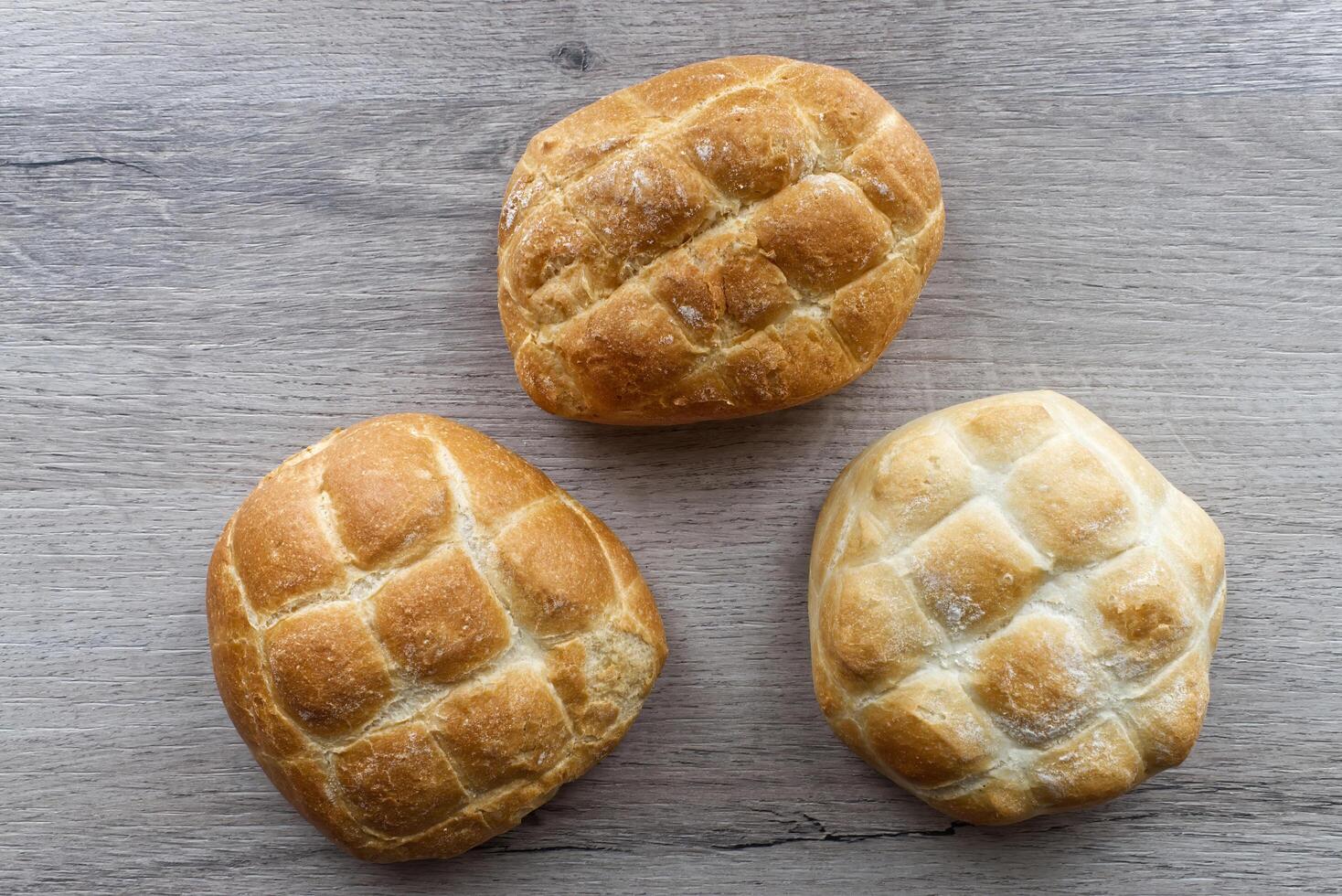 Three loaves of Italian bread rest on a wooden table. photo