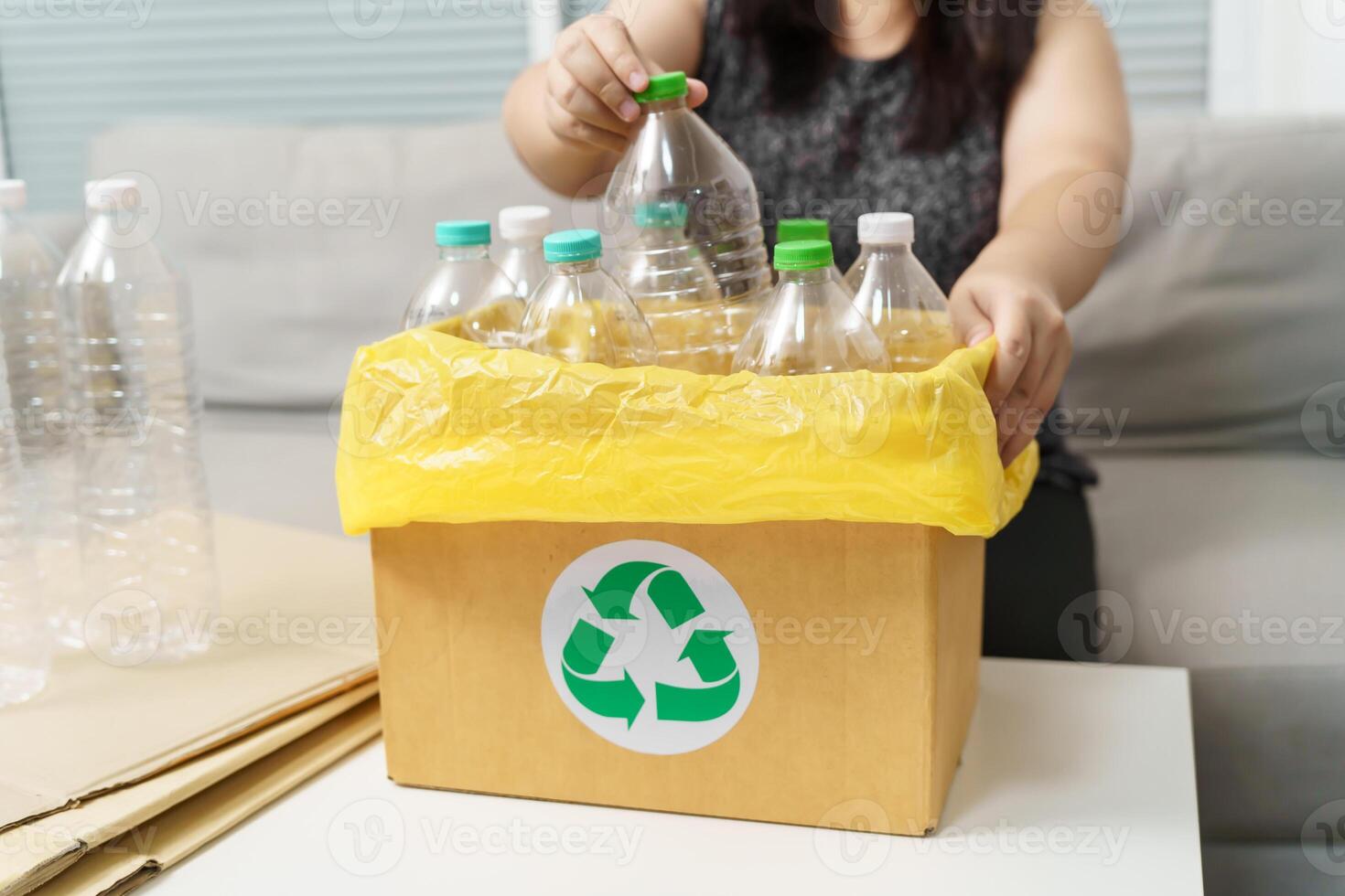 Home recycle eco green zero concept Woman throwing empty plastic bottle in recycling bin with yellow garbage bags at home. photo