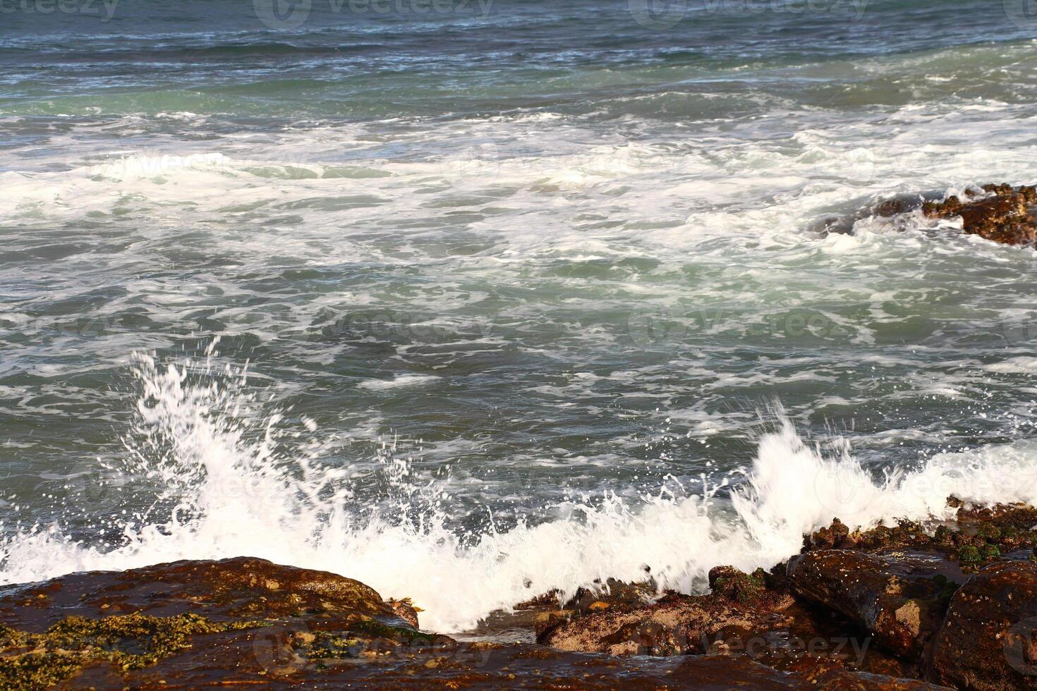Wave Splashing Against Rocky Coastline With Rough Waters Under Cloudy Sky photo