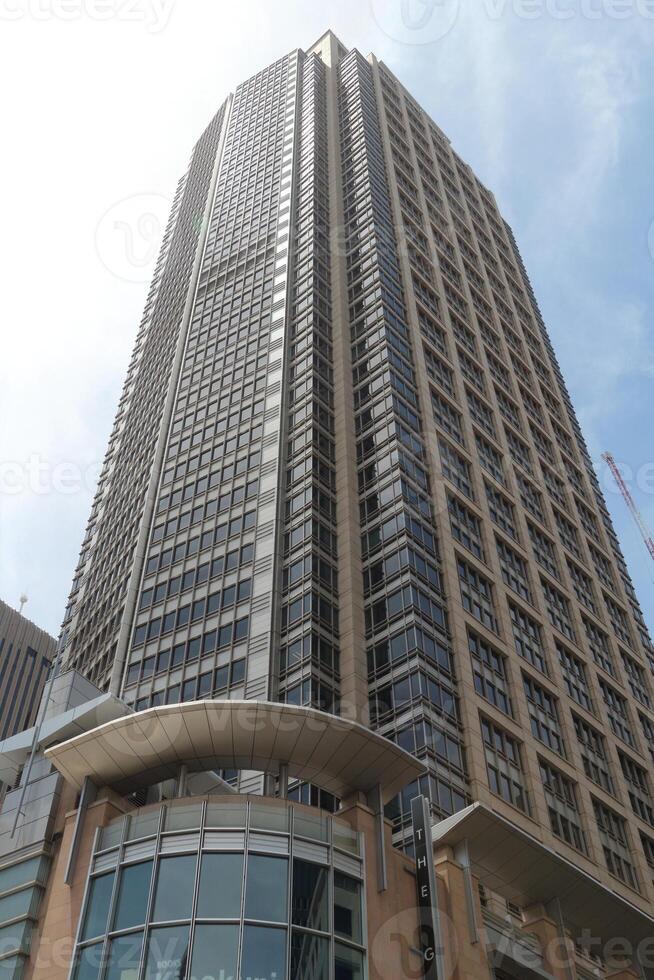 Tall Modern Skyscraper With Glass Windows Reaching Into The Sky On A Bright Sunny Day photo