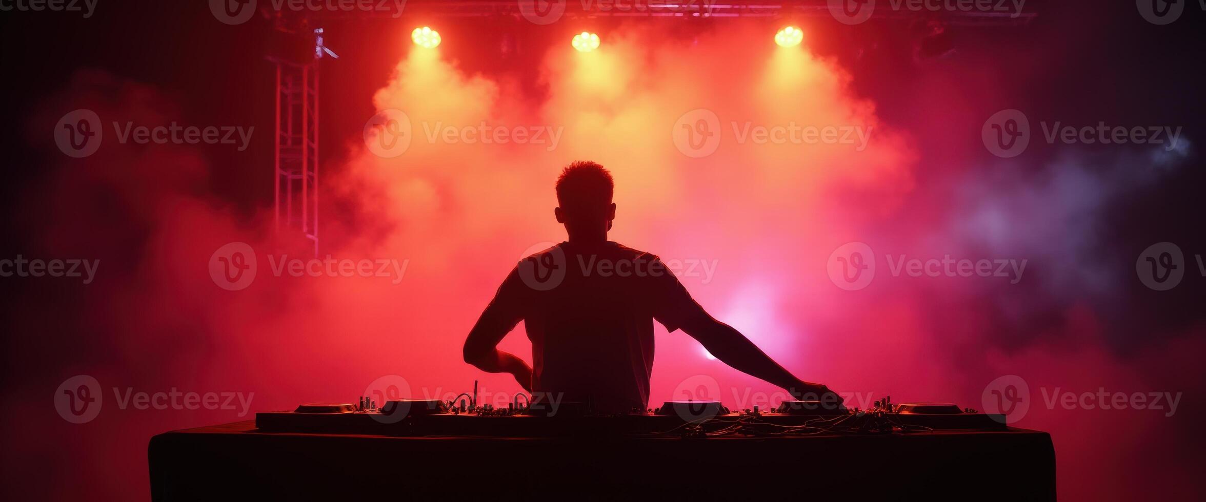 DJ performing with vibrant red and blue stage lights in a smoky atmosphere photo