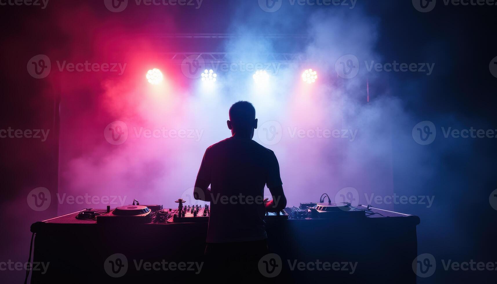 DJ performing with vibrant red and blue stage lights in a smoky atmosphere photo