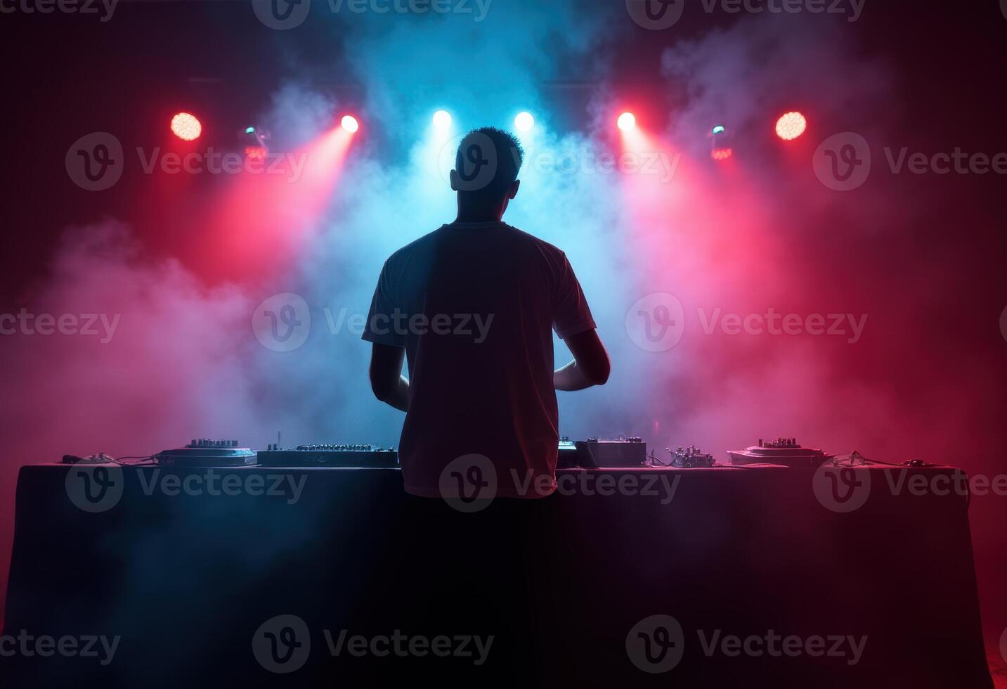 DJ performing with vibrant red and blue stage lights in a smoky atmosphere photo