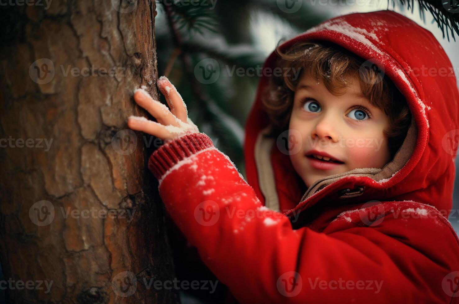 A boy in a red jacket plays outside near a tree in winter photo