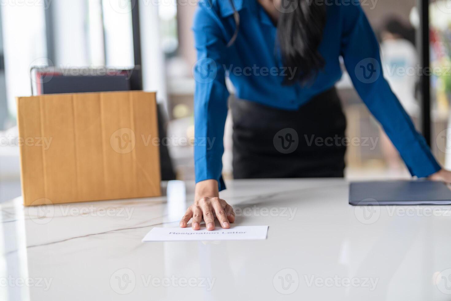 Business woman sending resignation letter and packing Stuff Resign Depress or carrying business cardboard box by desk in office. Change of job or fired from company photo
