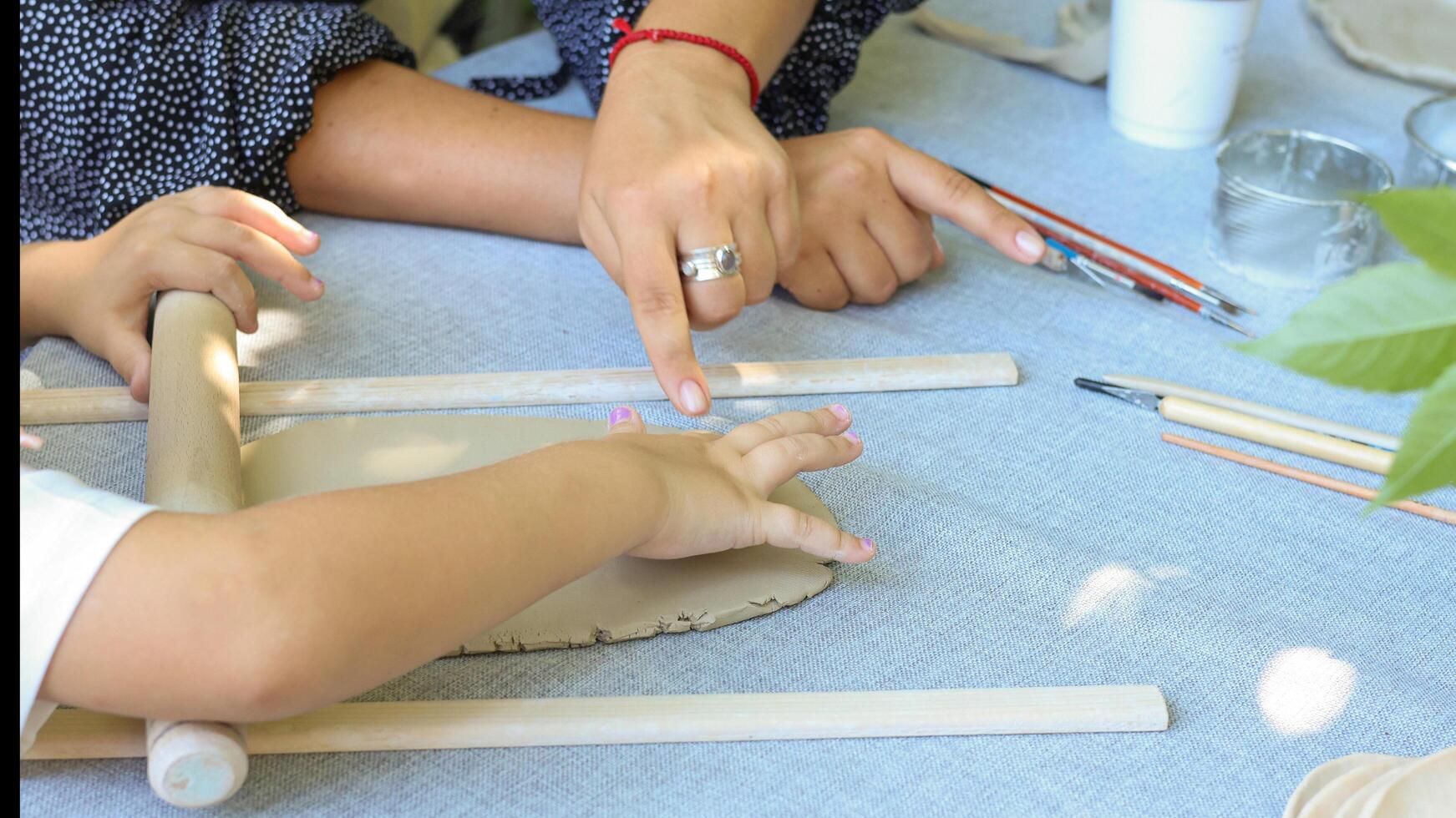 a child rolls natural-colored clay at a master class.children's creativity outside with adult photo