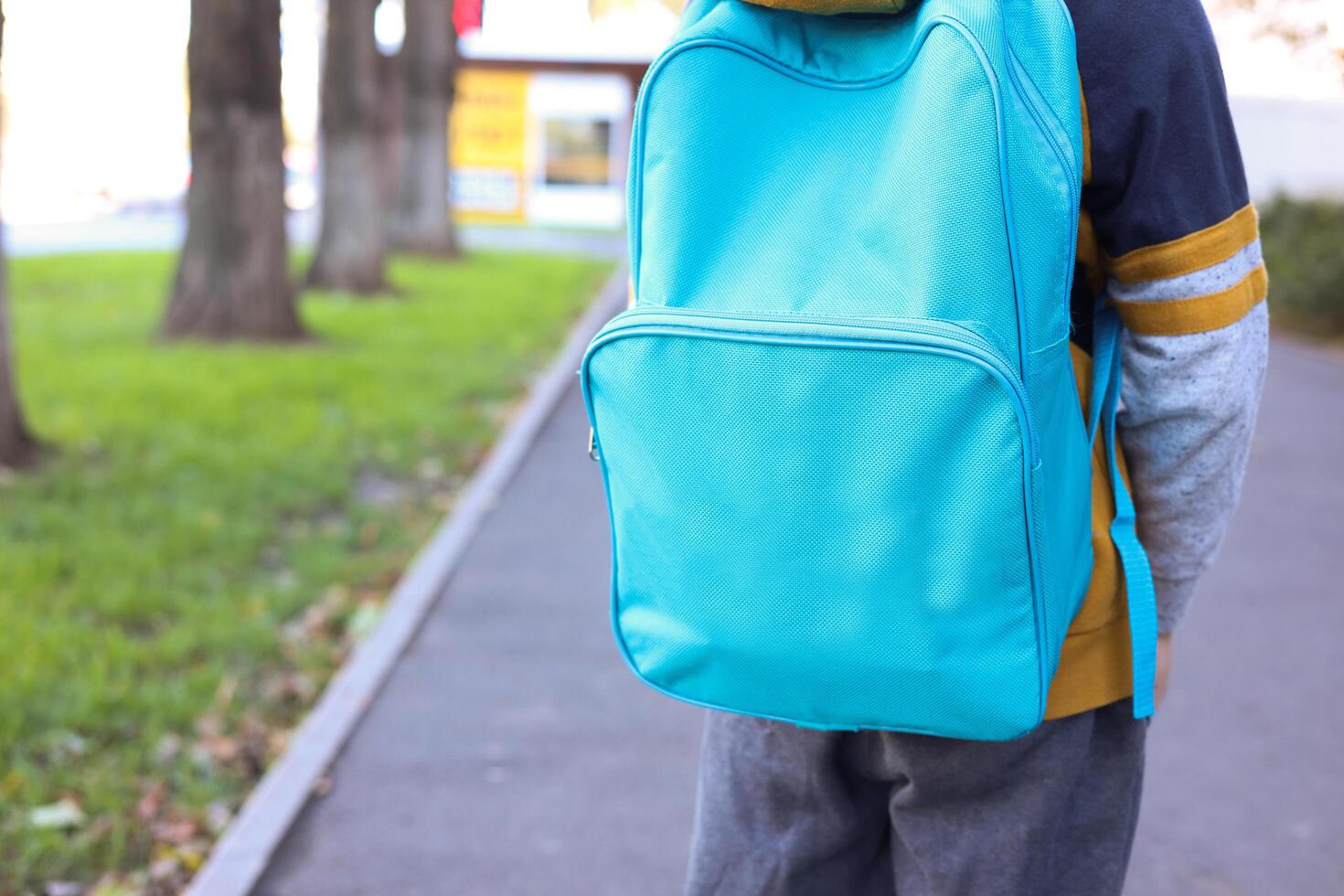 An 8-year-old boy stands with a backpack and a UNICEF logo on the street photo