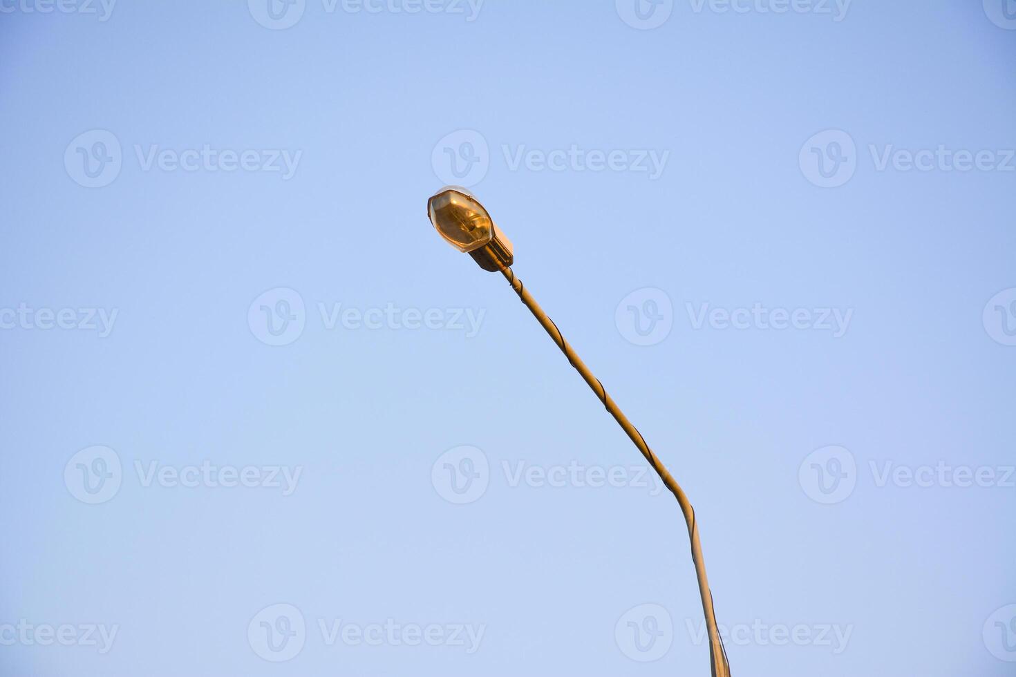 Standard lantern for street lighting. Street lamp on a metal pole against the blue sky. Powerful floodlight. photo