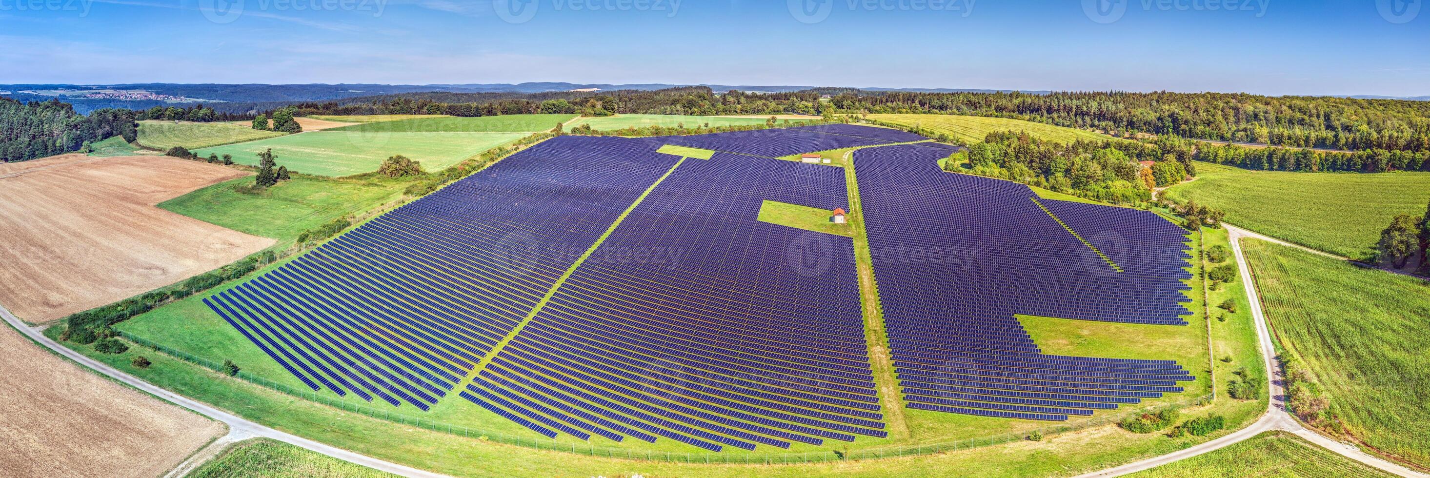 Panoramic image of a large solar field on a green meadow in daylight photo