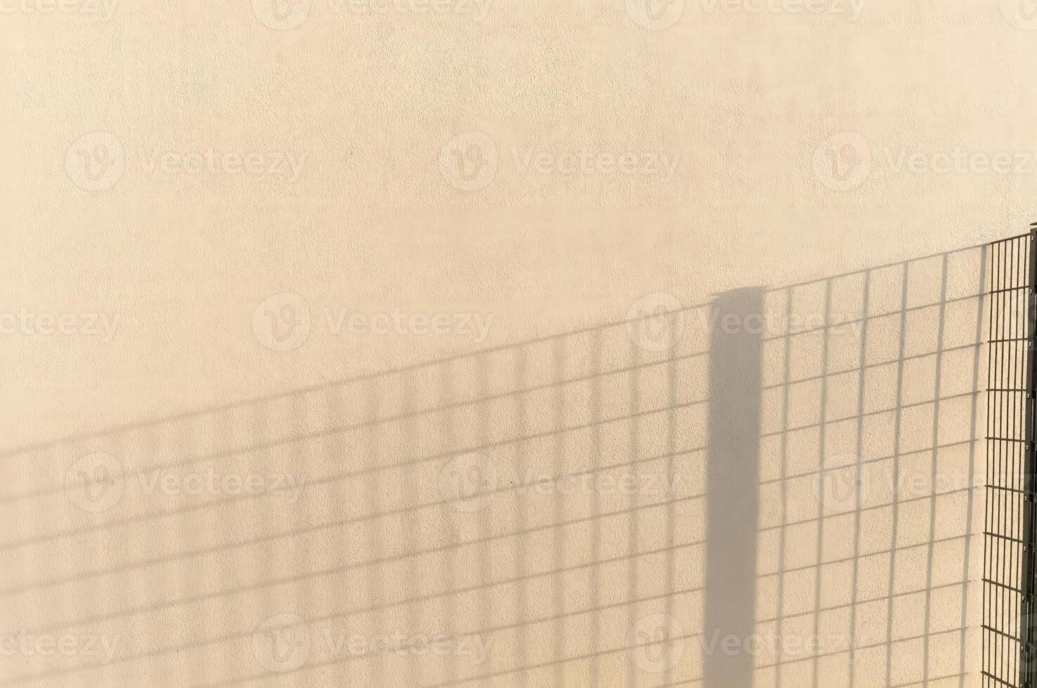 Shadow of fence creating geometric pattern on wall photo