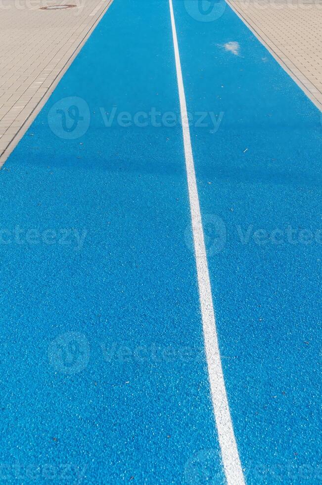 Running track texture with white stripe dividing the blue surface photo