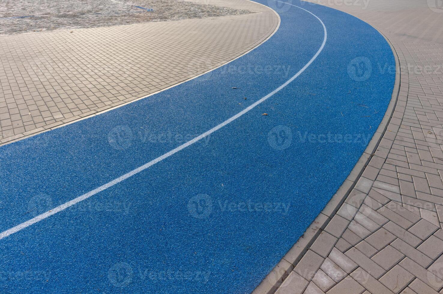 Blue running track curve surrounded by paving stones photo
