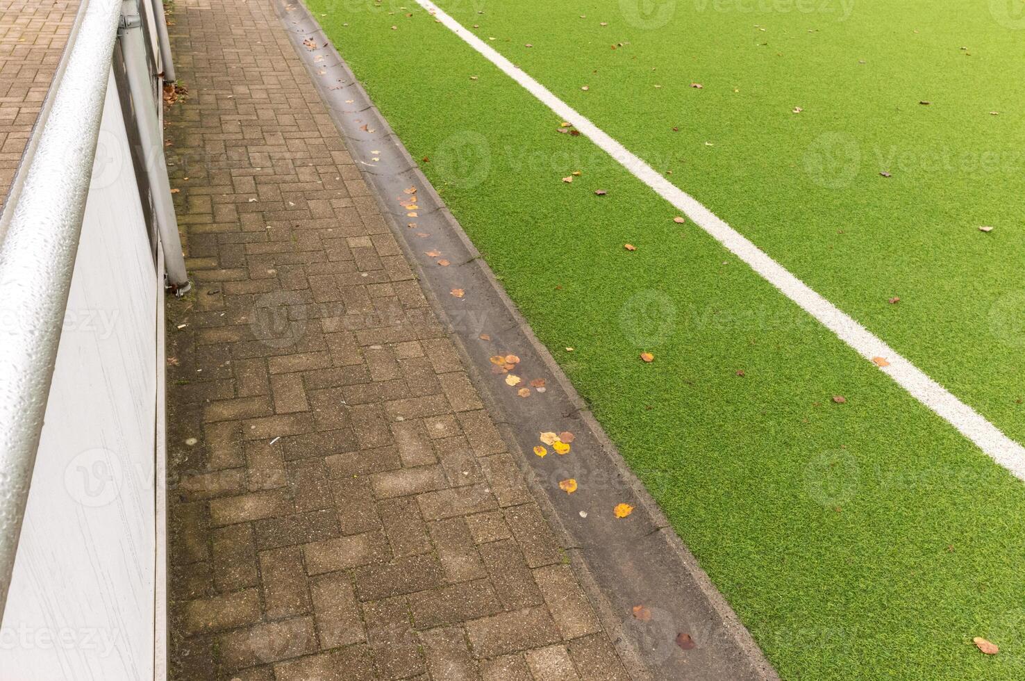 Autumn leaves falling on sideline of empty soccer field photo