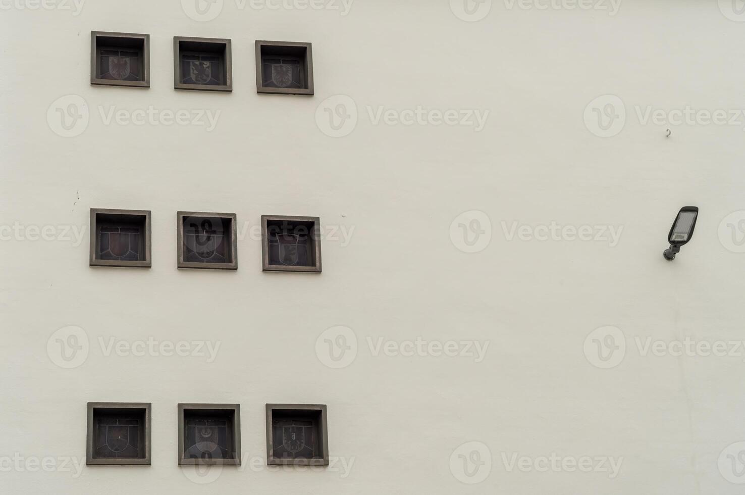 White wall showing nine square windows with a lamp on the right side photo