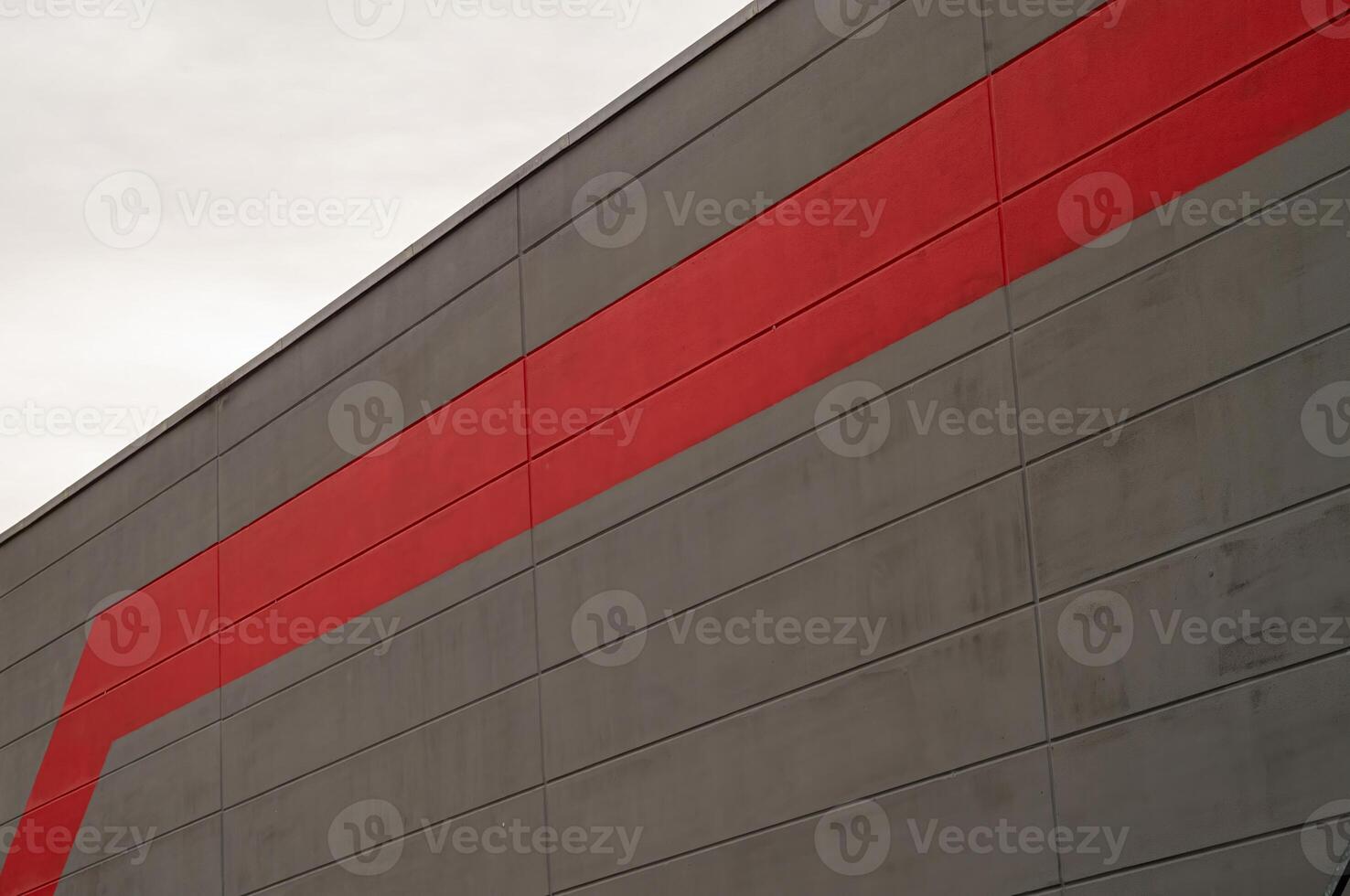 Red stripe cutting through a grey concrete modern building facade photo