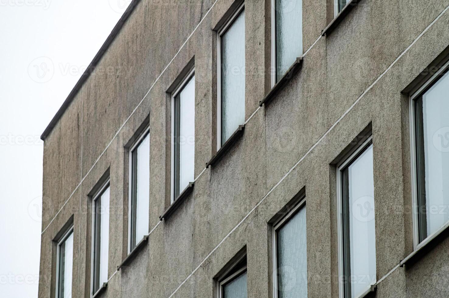 Grey concrete facade of modernist building showing windows and lines photo