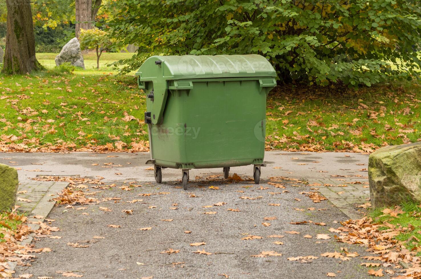 Green rolling garbage can on the footpath photo