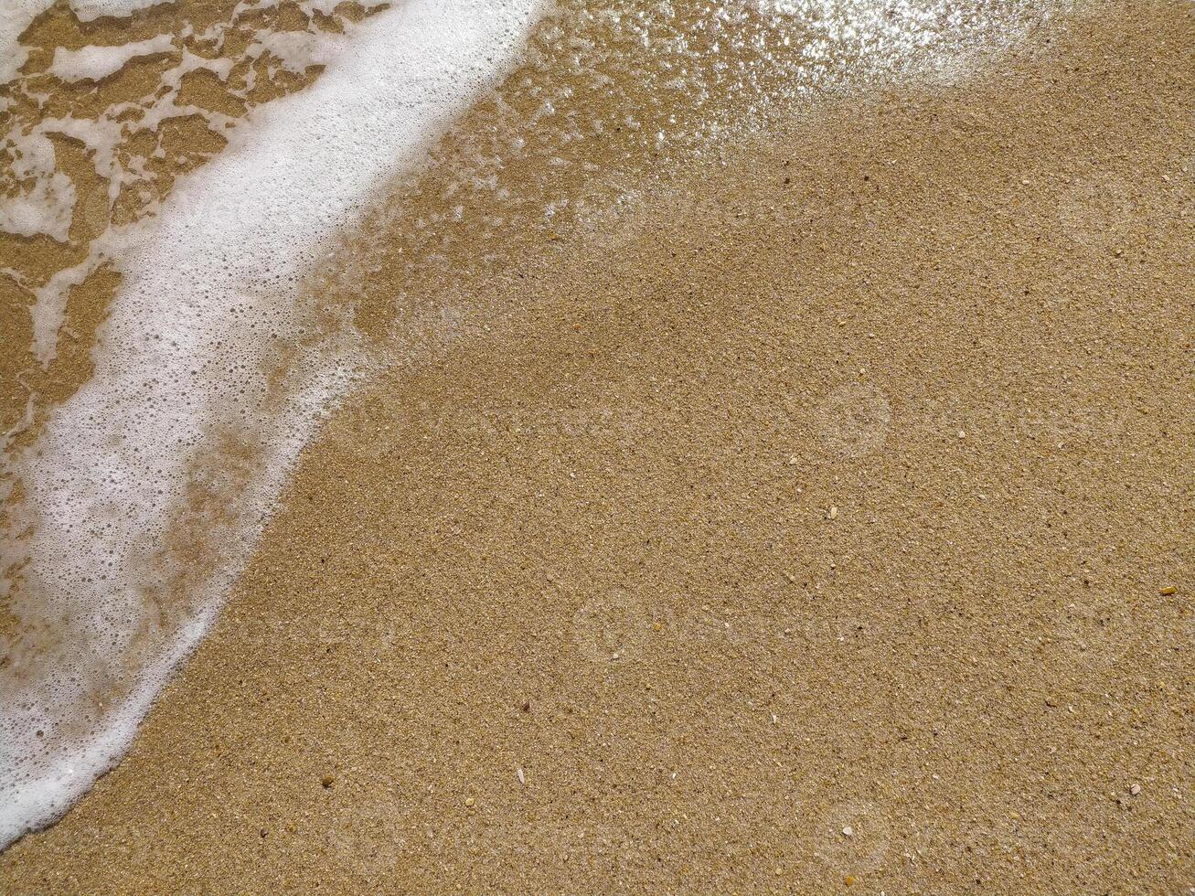 Fine golden sand covering a beach during a sunny day with clear skies, creating a serene and tranquil atmosphere for relaxation photo