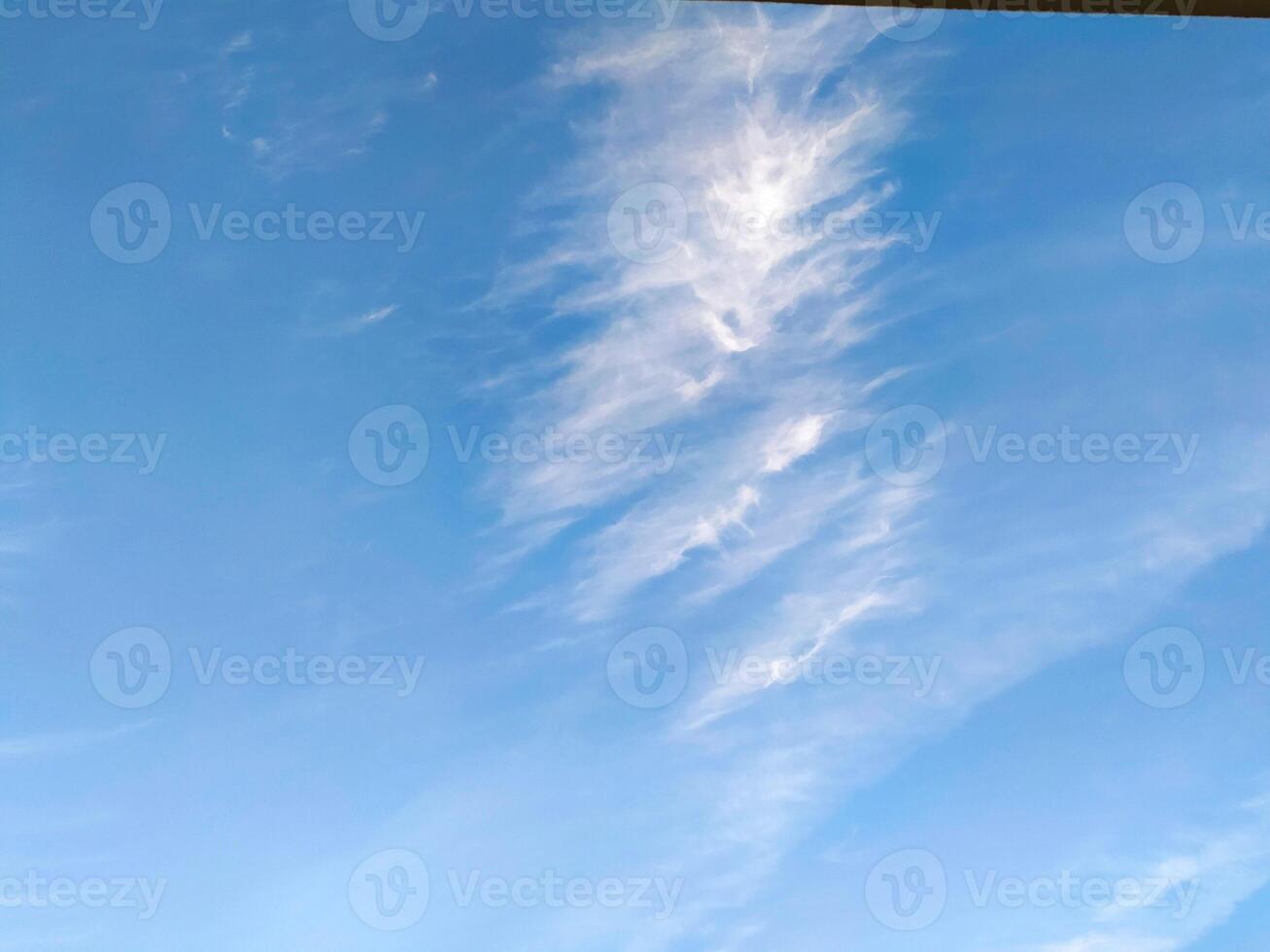 A clear blue sky with fluffy white clouds drifting lazily during a sunny afternoon in a serene outdoor setting photo