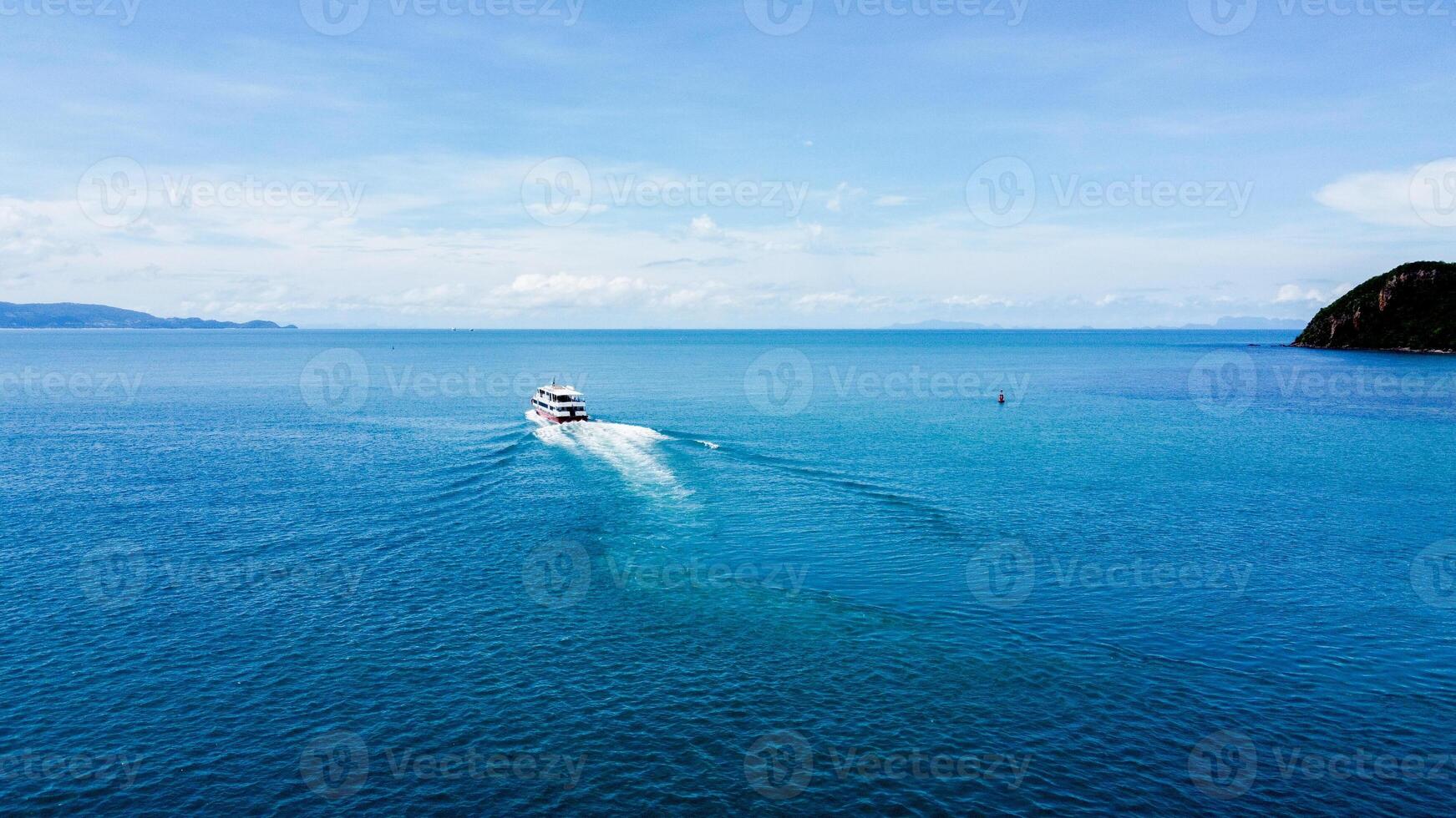 Aerial View of a Yacht Sailing on the Open Sea with Clear Blue Skies and Distant Horizon on a Sunny Day photo