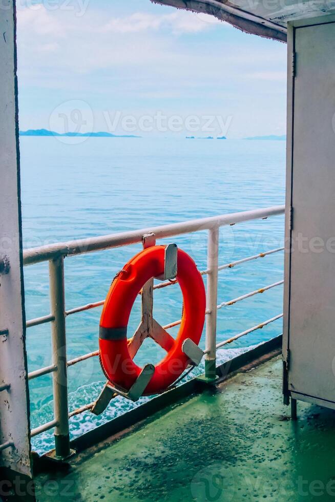 Scenic View from a Ferry Deck with a Vibrant Orange Lifebuoy Overlooking the Calm Blue Sea and Distant Islands photo