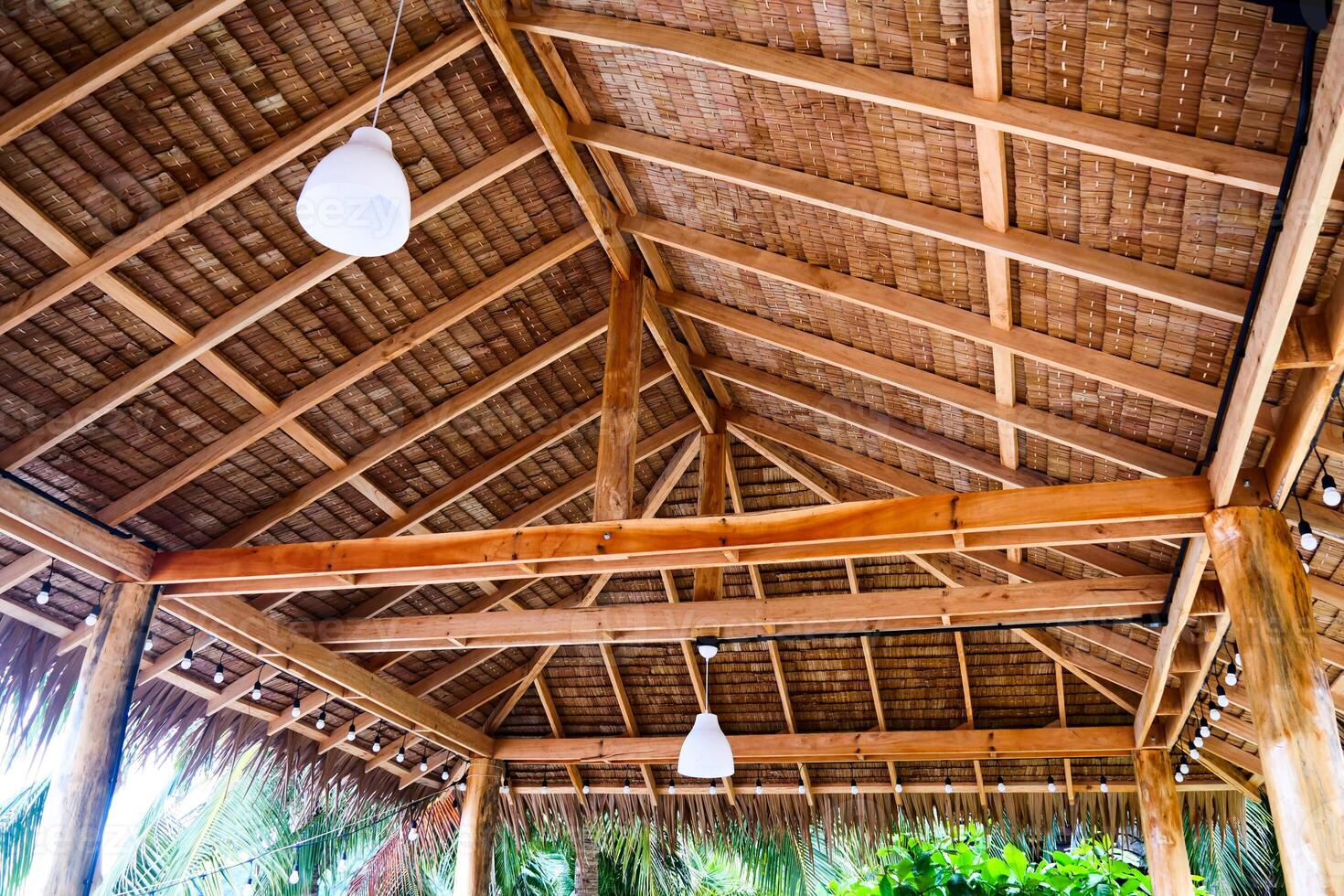 Rustic Wooden Ceiling with Exposed Beams and Hanging Lights in Tropical Outdoor Setting photo